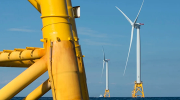 Wind turbines in the ocean near a large yellow pole: harnessing renewable energy from the sea.