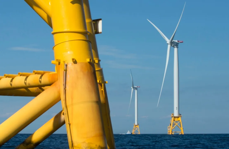 Wind turbines in the ocean near a large yellow pole: harnessing renewable energy from the sea.