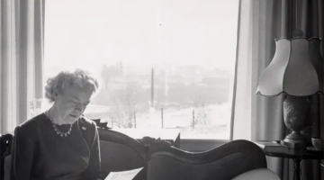 Margaret Chase Smith reading a document sitting on a couch. in her Skowhegan Maine home.