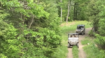 Two ATVs drive down a wooded path to represent the Bangor Daily News article on gas taxes.