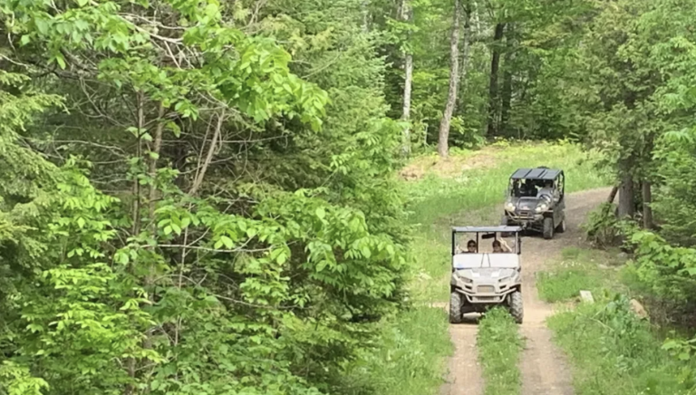 Two ATVs drive down a wooded path to represent the Bangor Daily News article on gas taxes.