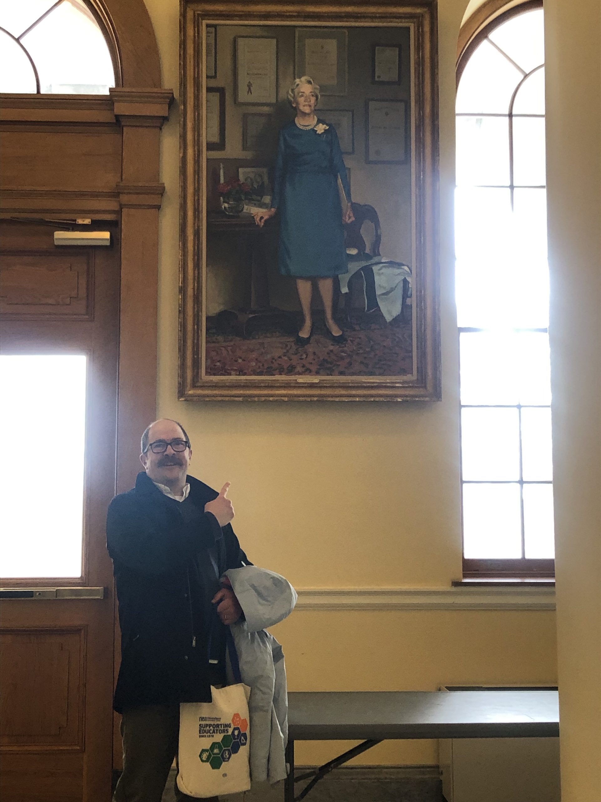 Michael Scott poses with Senator Margaret Chase Smith's portrait at the Maine State House.